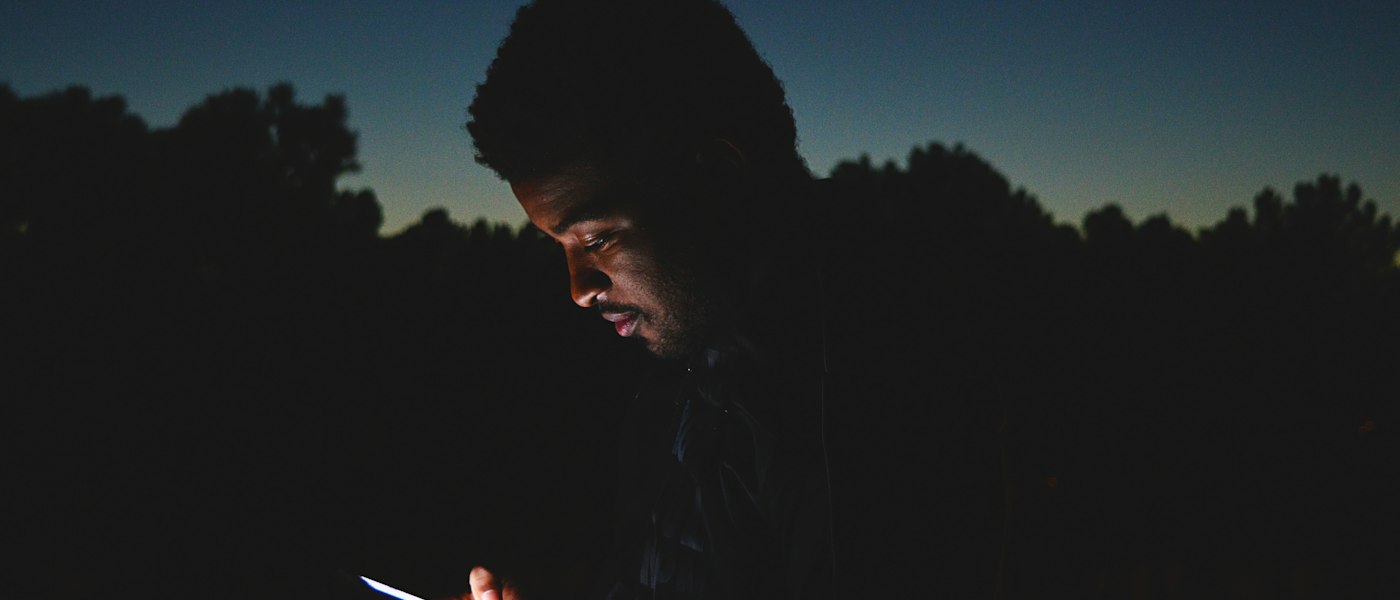 Visage éclairé par l’écran d’un téléphone, la nuit — être joignable en dehors des heures