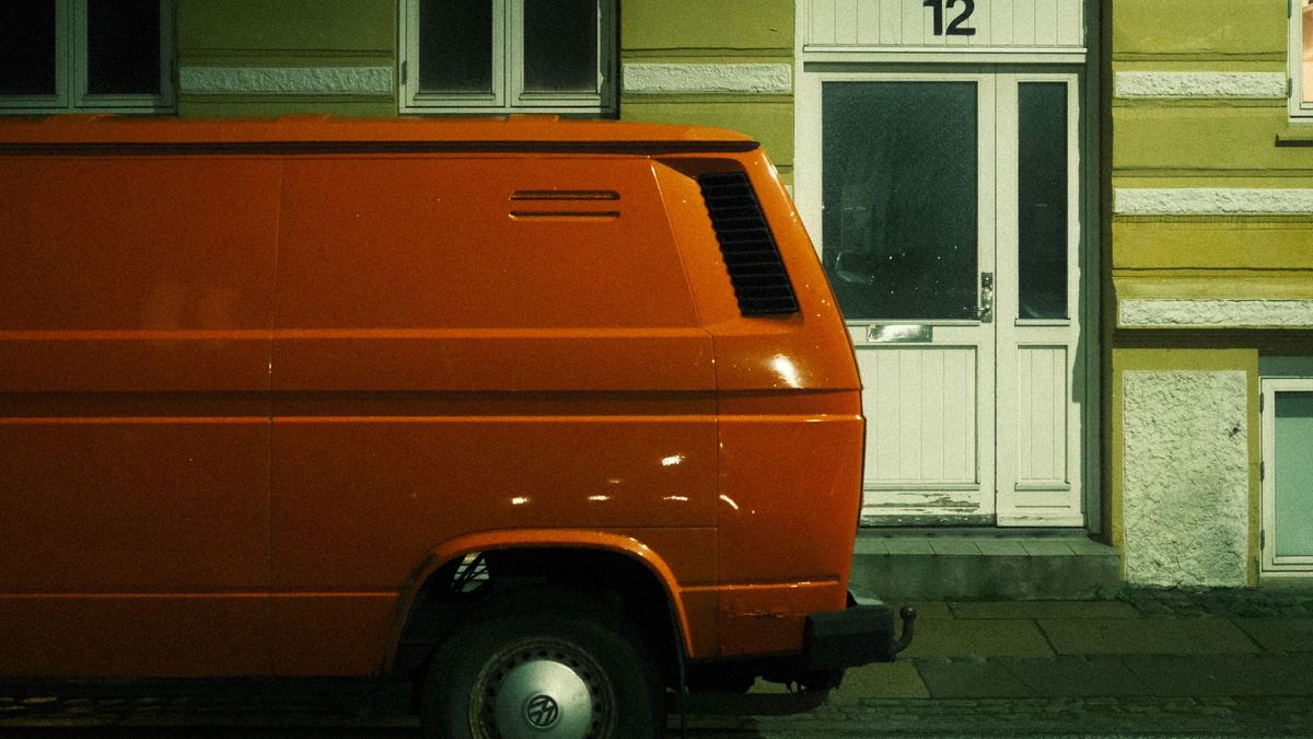Camionnette orange garée la nuit devant la porte d’un immeuble