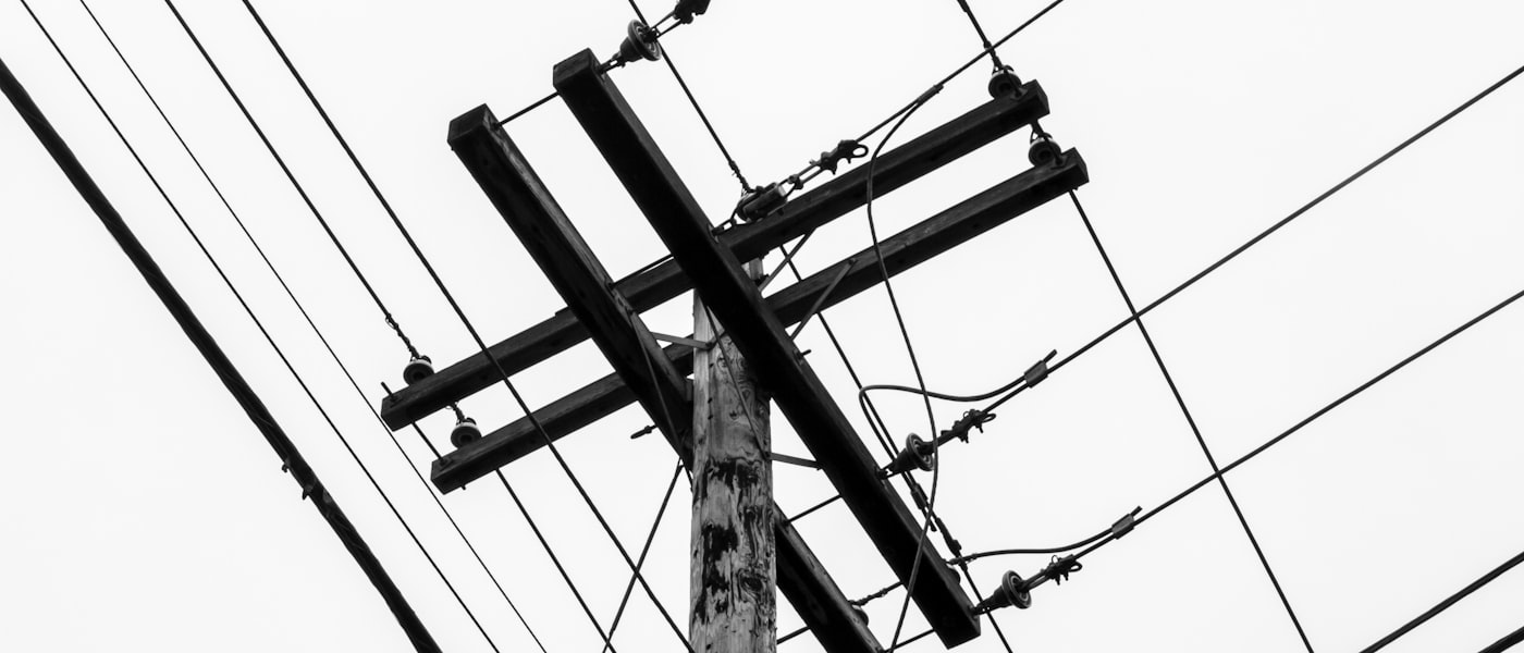 Traverse d’une ligne téléphonique aérienne et ses fils, sous un ciel gris