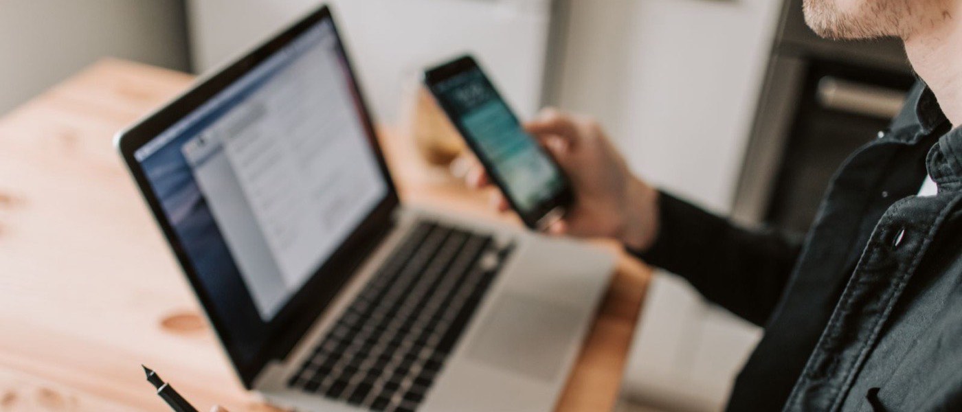 Un professionnel consulte son smartphone à son bureau, à côté d’un ordinateur portable et d’un carnet