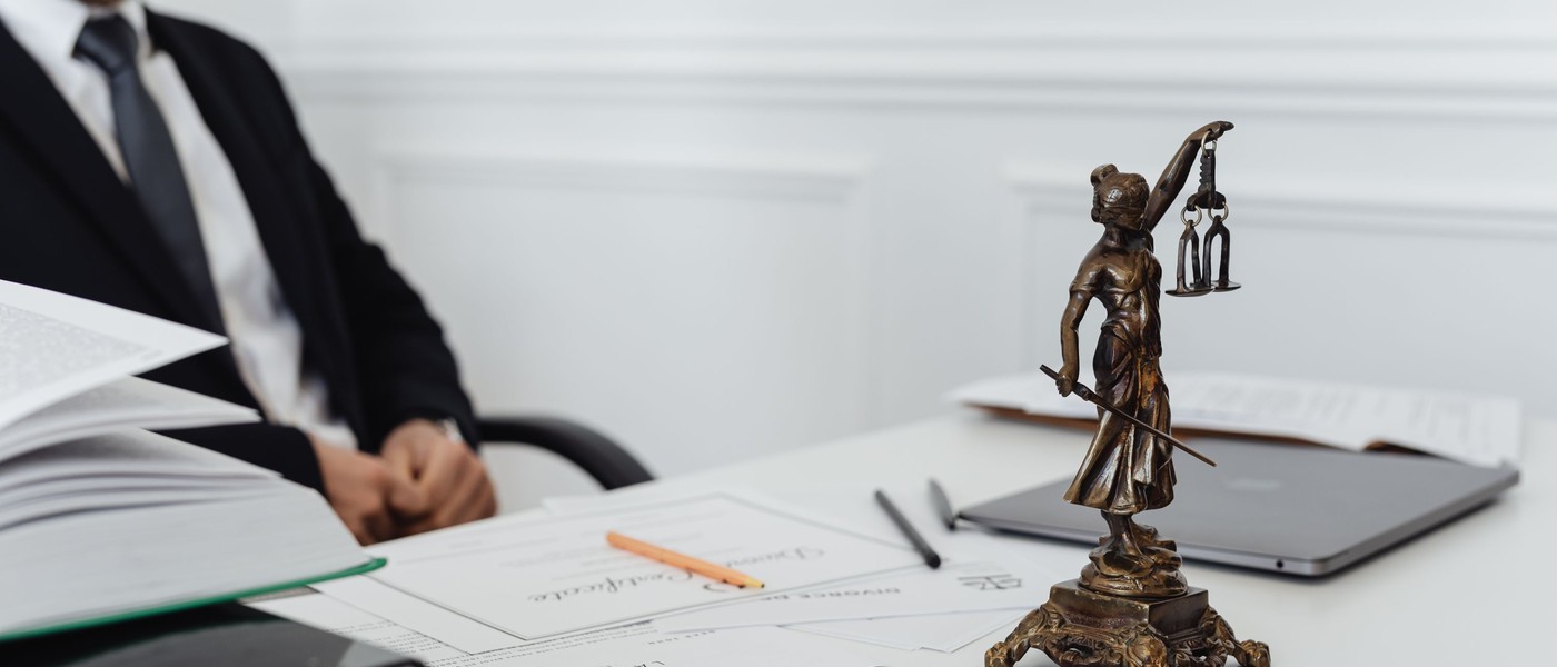 Bureau de cabinet d’avocat avec une statuette de la justice, des actes et un ordinateur portable